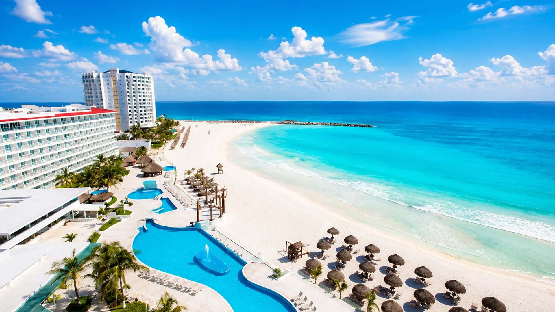 Aerial view of a Cancun resort's guitar-shaped pool along the beach