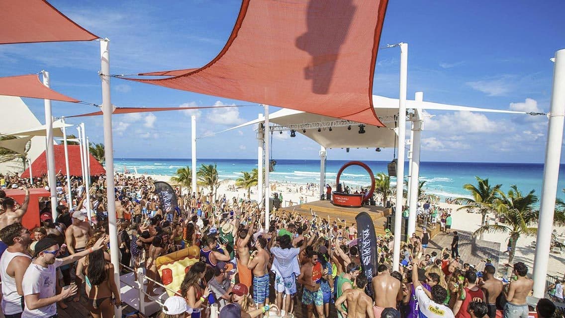 a crowd of people standing on top of a sandy beach.