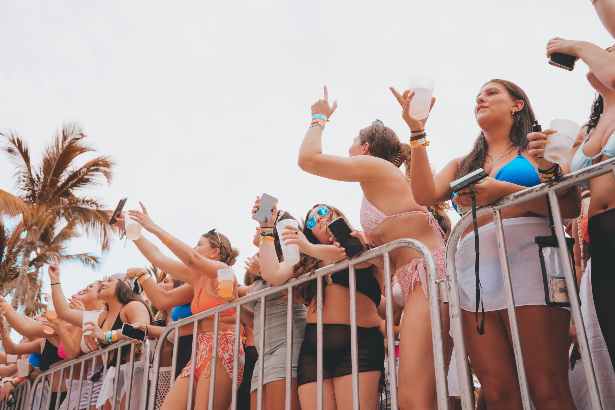 a crowd of people standing next to a metal fence.